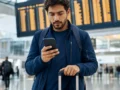 Ida e volta em companhias diferentes: quando vale a pena e quais cuidados tomar - destacada: Passageiro consultando voos de ida e volta em companhias diferentes no aeroporto