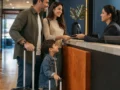 Criança paga diária em hotel? Entenda as regras antes de reservar - destacada: Família com criança fazendo check-in em hotel, ilustrando regras de diária infantil