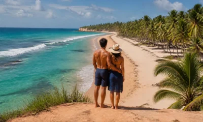 Melhores destinos do Nordeste: como escolher a viagem ideal - Casal observando praia de águas claras entre coqueiros em um dos melhores destinos do Nordeste
