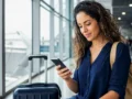 Cartão de embarque: como obter, usar no celular e evitar imprevistos - Passageira consultando cartão de embarque digital no celular dentro de um aeroporto