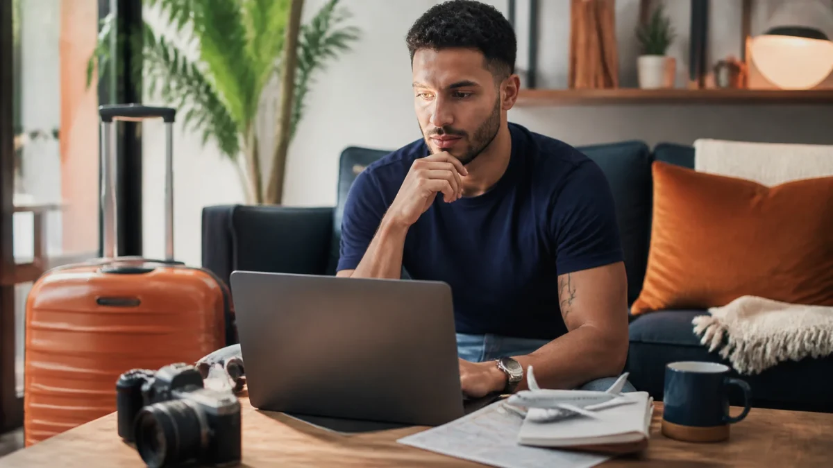 Como emitir passagem Smiles e comparar milhas, taxas e dinheiro - Passageiro pesquisando como emitir passagem Smiles em notebook antes de uma viagem