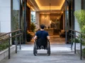 Como escolher hotel acessível e confirmar adaptações antes da reserva - Hóspede cadeirante entrando em hotel acessível com rampa na entrada