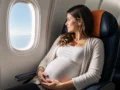 Gestante pode viajar de avião? Cuidados, documentos e limites - Gestante sentada próxima à janela de um avião durante viagem
